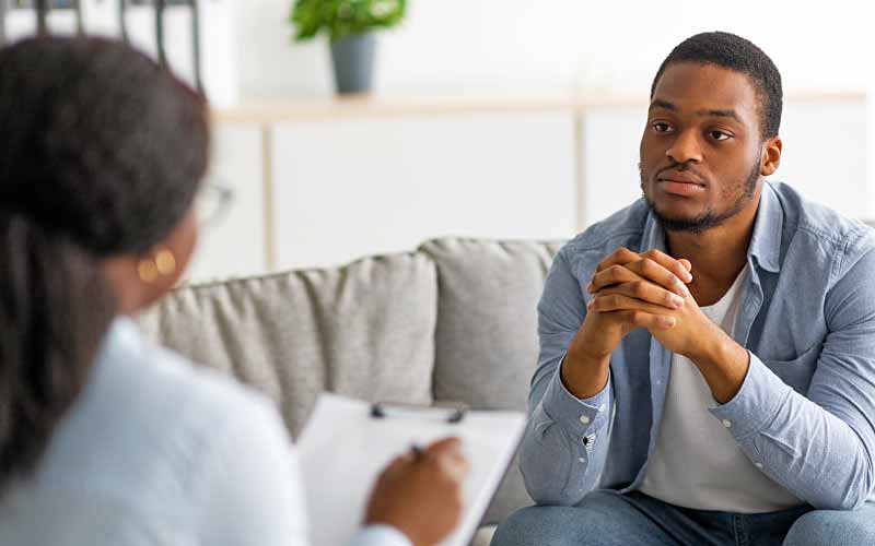 Upset woman frustrated by problem with work or relationships, sitting on couch.